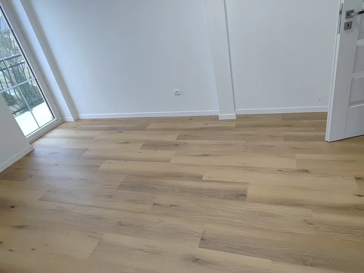 Drugi pokój z wyjściem na balkon, deski ułożone z przesunięciem, listwy dopasowane do ościeżnicy i narożników